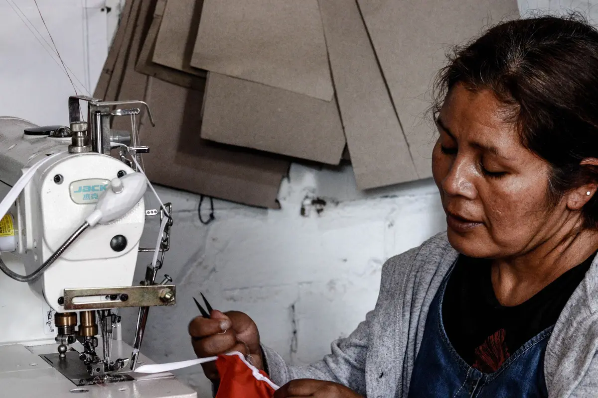 Mujer cosiendo con su máquina en un taller de Trujillo, Perú