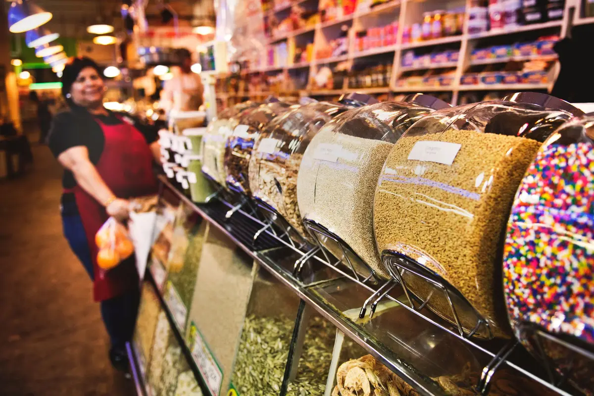 Vendedora sonriente en un mercado de abarrotes a granel
