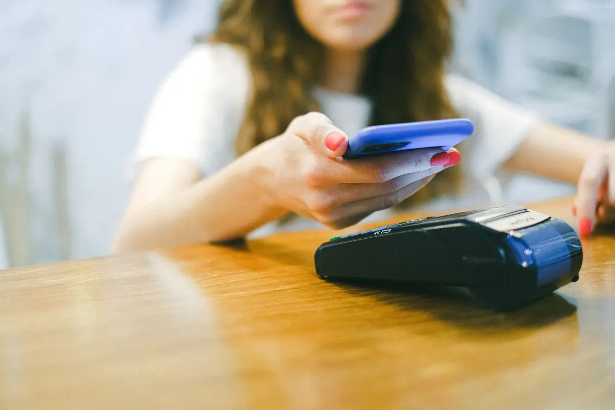 Mujer pagando con el celular en un terminal de pago