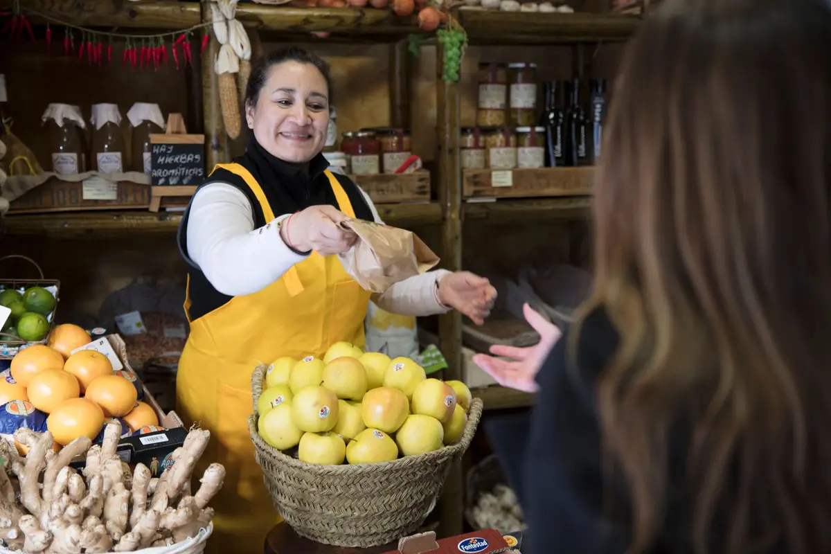 Vendedora sonriente entregando una bolsa a una clienta en su tienda
