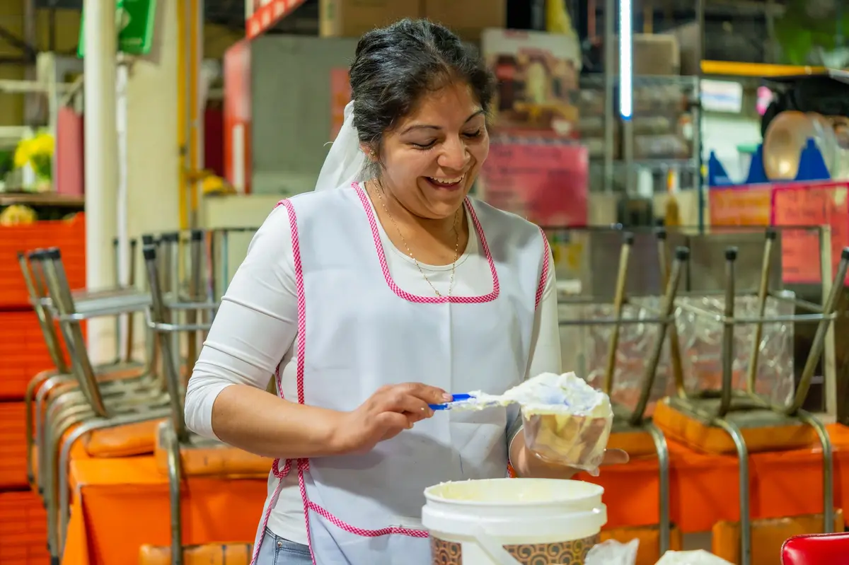 Mujer con mandil preparando comida en su puesto de un mercado