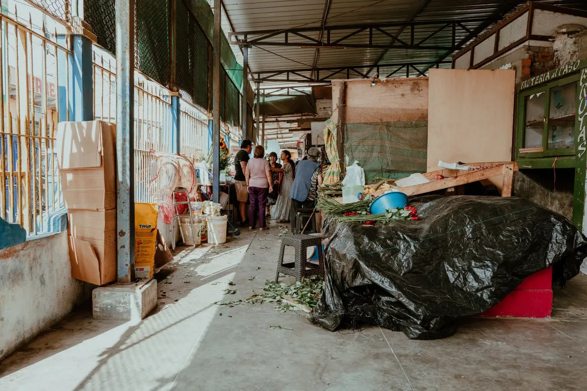Pasillo de un mercado techado con puestos y compradores al fondo