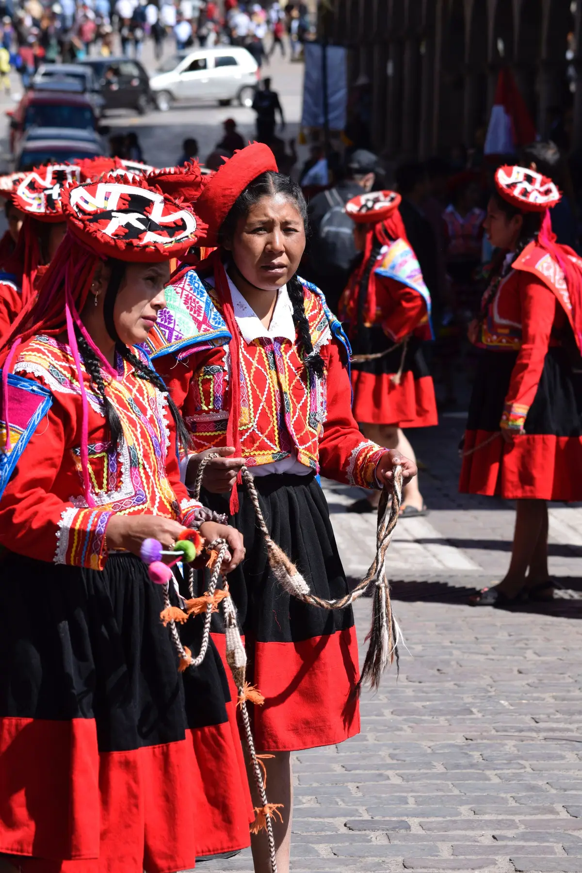 Grupo de mujeres con ropa andina tradicional en una calle durante una fiesta