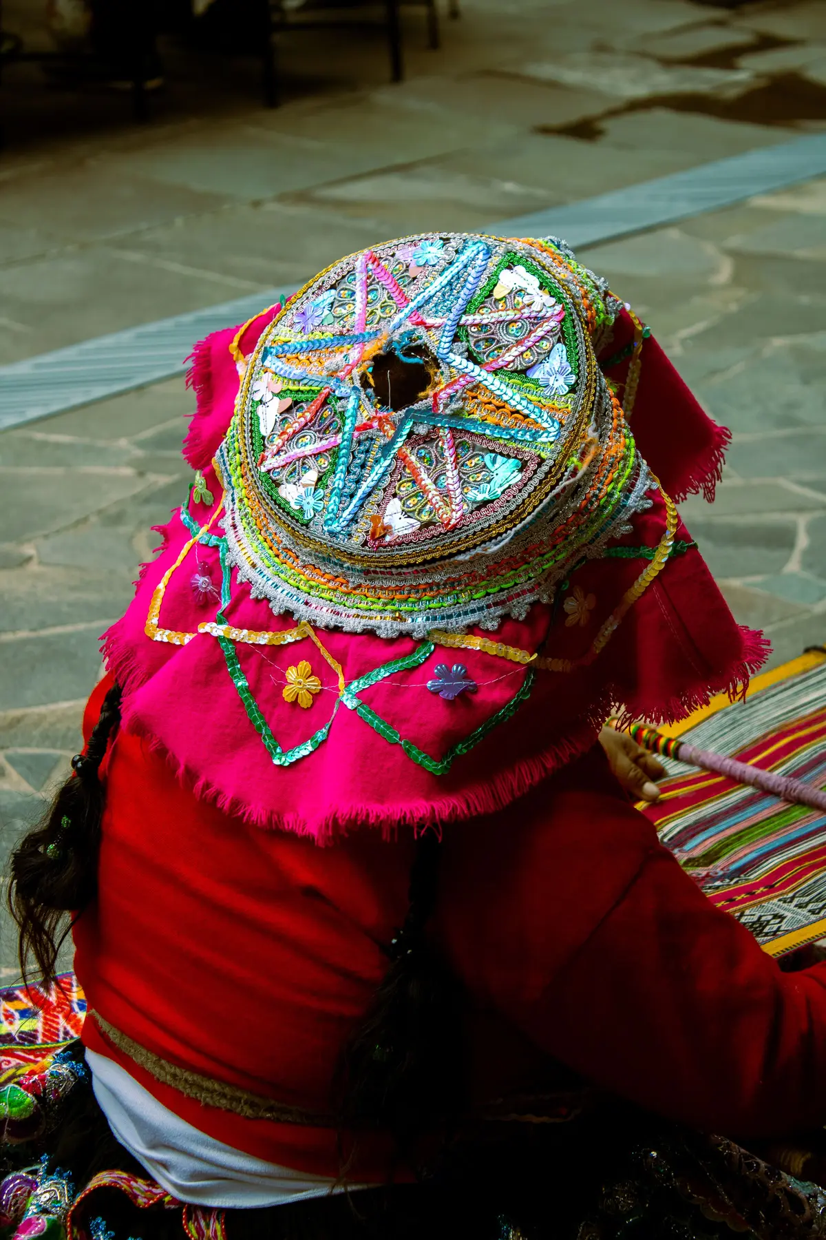 Mujer con montera bordada y traje tradicional cusqueño sentada en una plaza