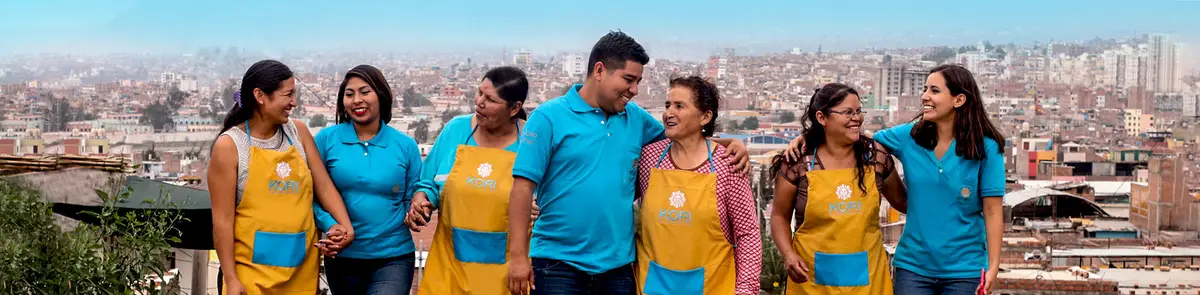 Socias con mandil Kori y asesores de polo celeste abrazados sobre un mirador de la ciudad