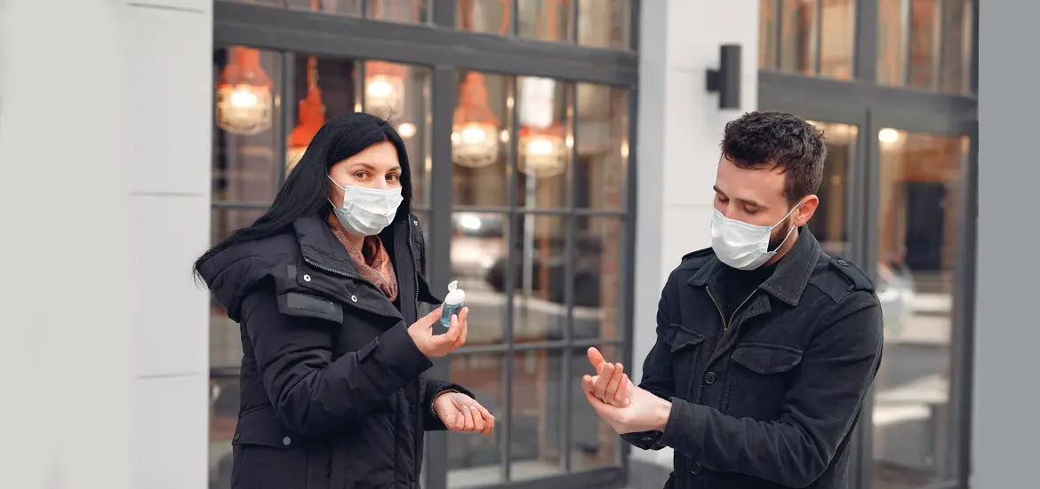 Dos personas con mascarilla y alcohol en la calle