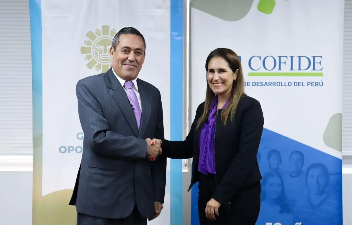 Representantes de Kori y COFIDE se dan la mano frente a banners de ambas entidades