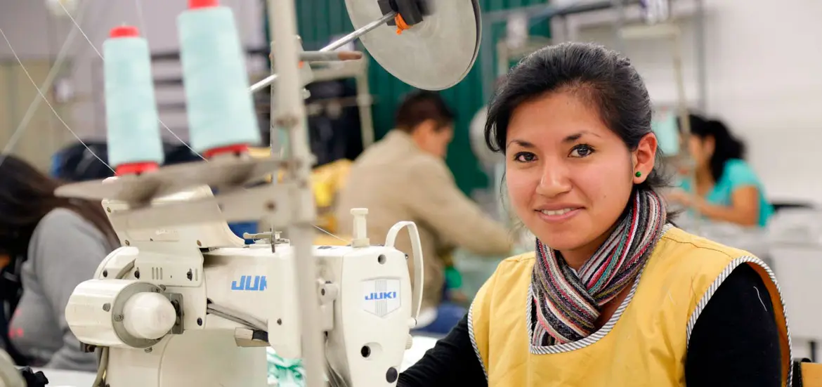 Joven costurera con chaleco amarillo en un taller de confección